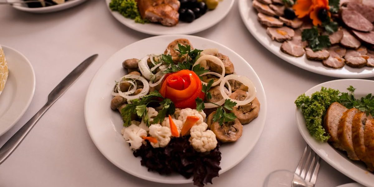 Beautifully arranged gourmet plates with meats, cheeses, and garnishes on a white table setting.